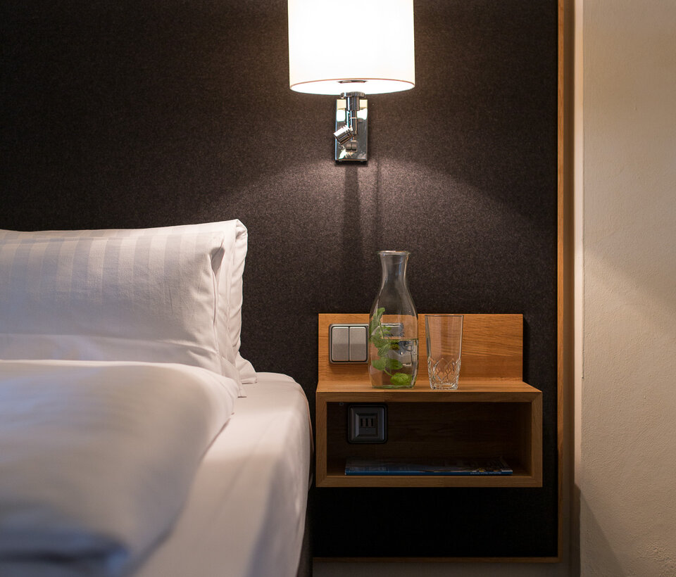 Nachttisch mit Lampe im Hotelzimmer Detailansicht eines Nachttischs mit Lampe und Bett im Hotelzimmer des Hotel-Landgasthof KREUZ