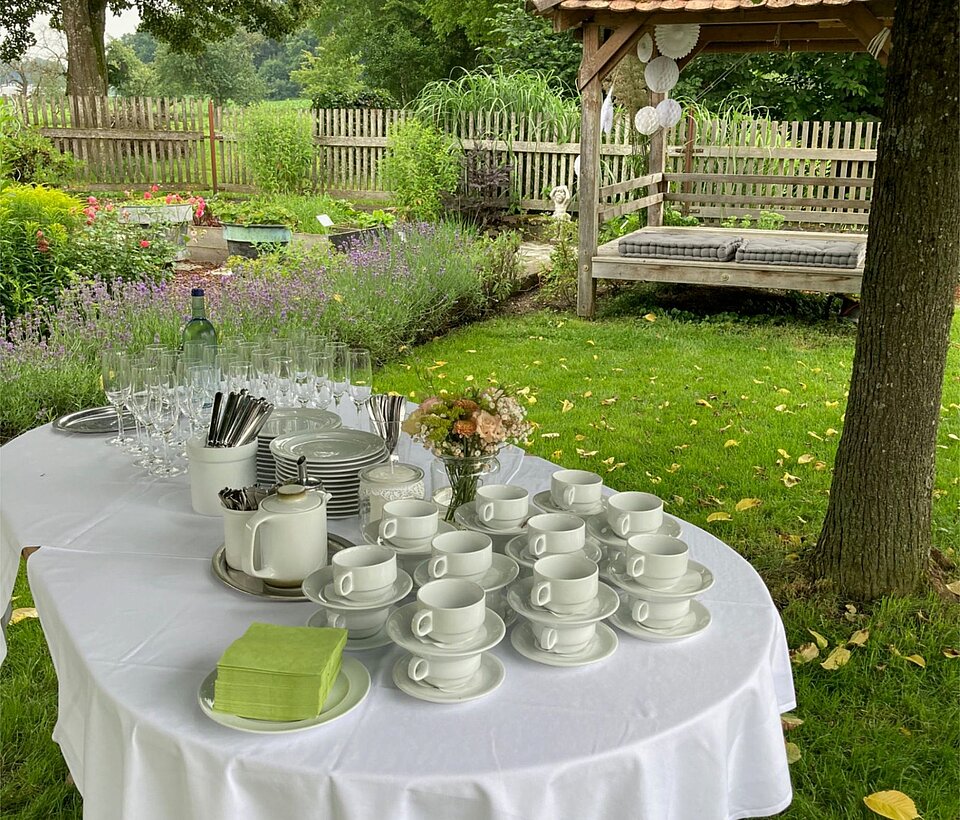 Gartentisch festlich eingedeckt Rund gedeckter Tisch mit weißer Tischdecke im Garten