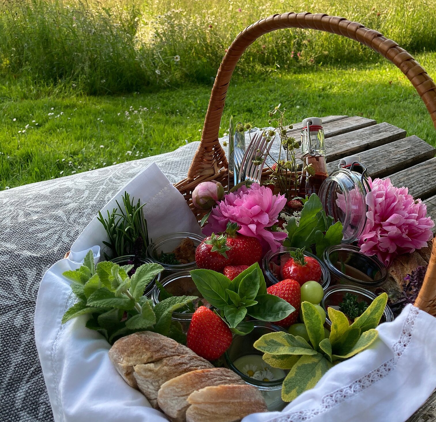 Picknickkorb Picknickkorb steht auf einem Holztisch im Grünen