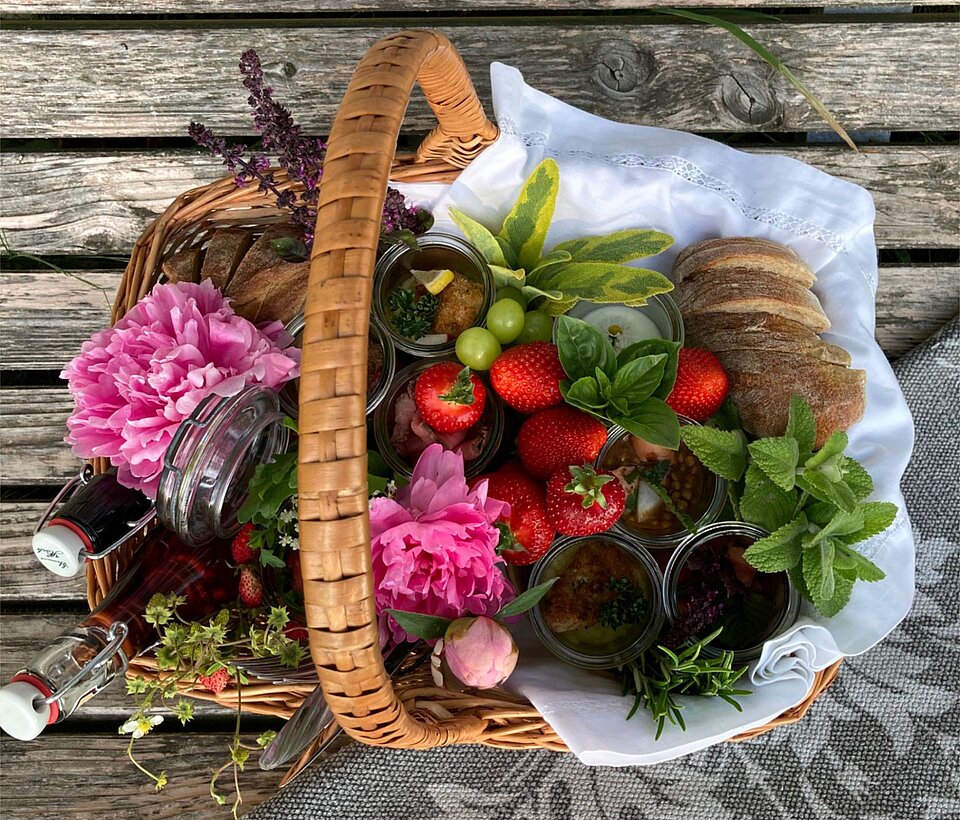 Gartenkorb mit Ernte und Blüten Bunter Korb mit Blumen und Gemüse auf Holzboden
