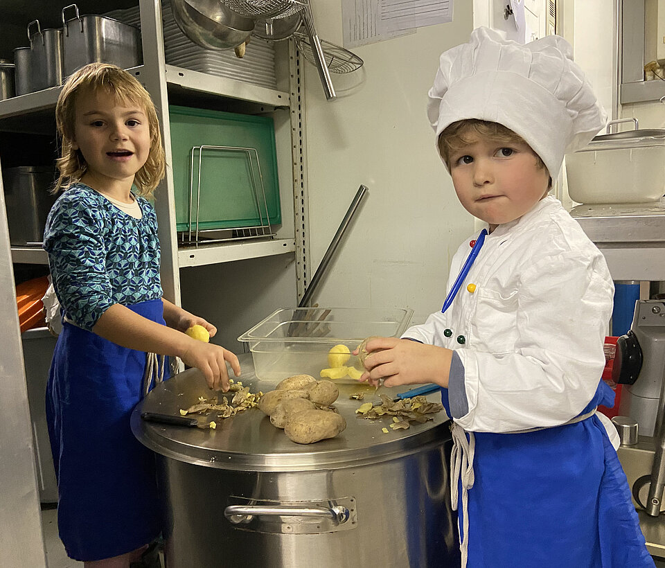 Teamarbeit in der Küche Zwei Kinder gemeinsam an großen Töpfen in der Küche