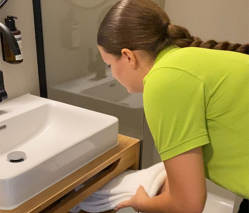 Servicepersonal im Zimmer Servicepersonal füllt Handtücher auf