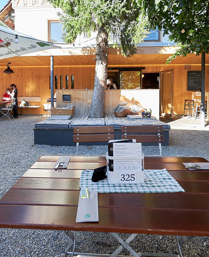 Großer Gastraum mit Fensterfront Gastraum mit langen Holztischen, Stühlen und Fensterfront