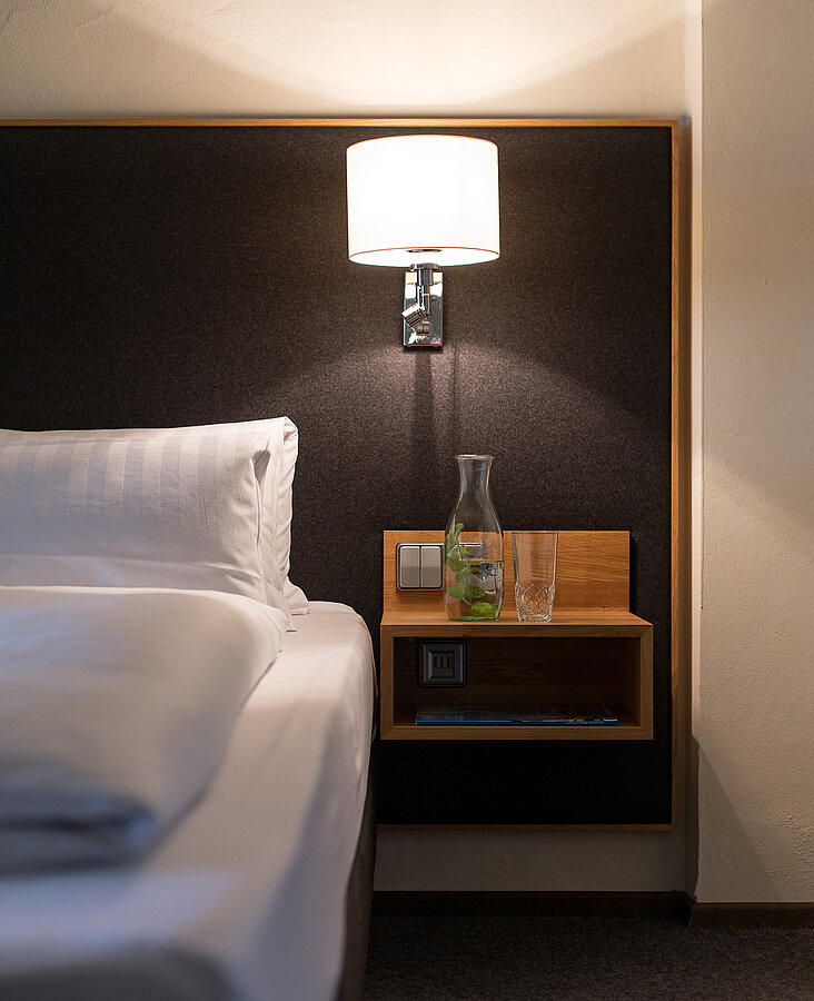 Nachttisch mit Lampe im Hotelzimmer Detailansicht eines Nachttischs mit Lampe und Bett im Hotelzimmer des Hotel-Landgasthof KREUZ